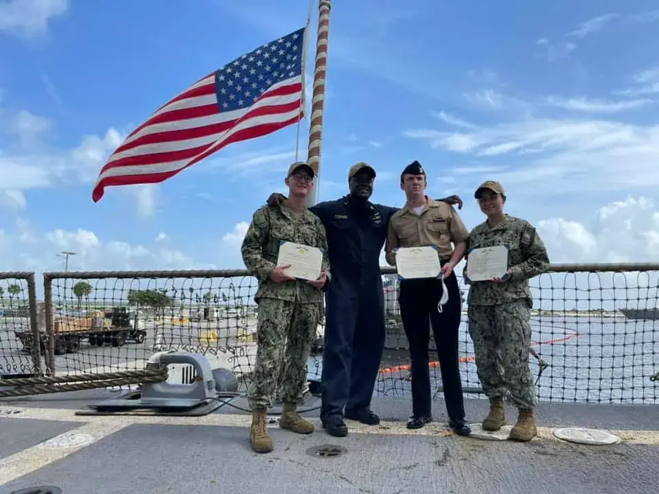 Austin Barrett with fellow sailors on deck under the U.S. flag