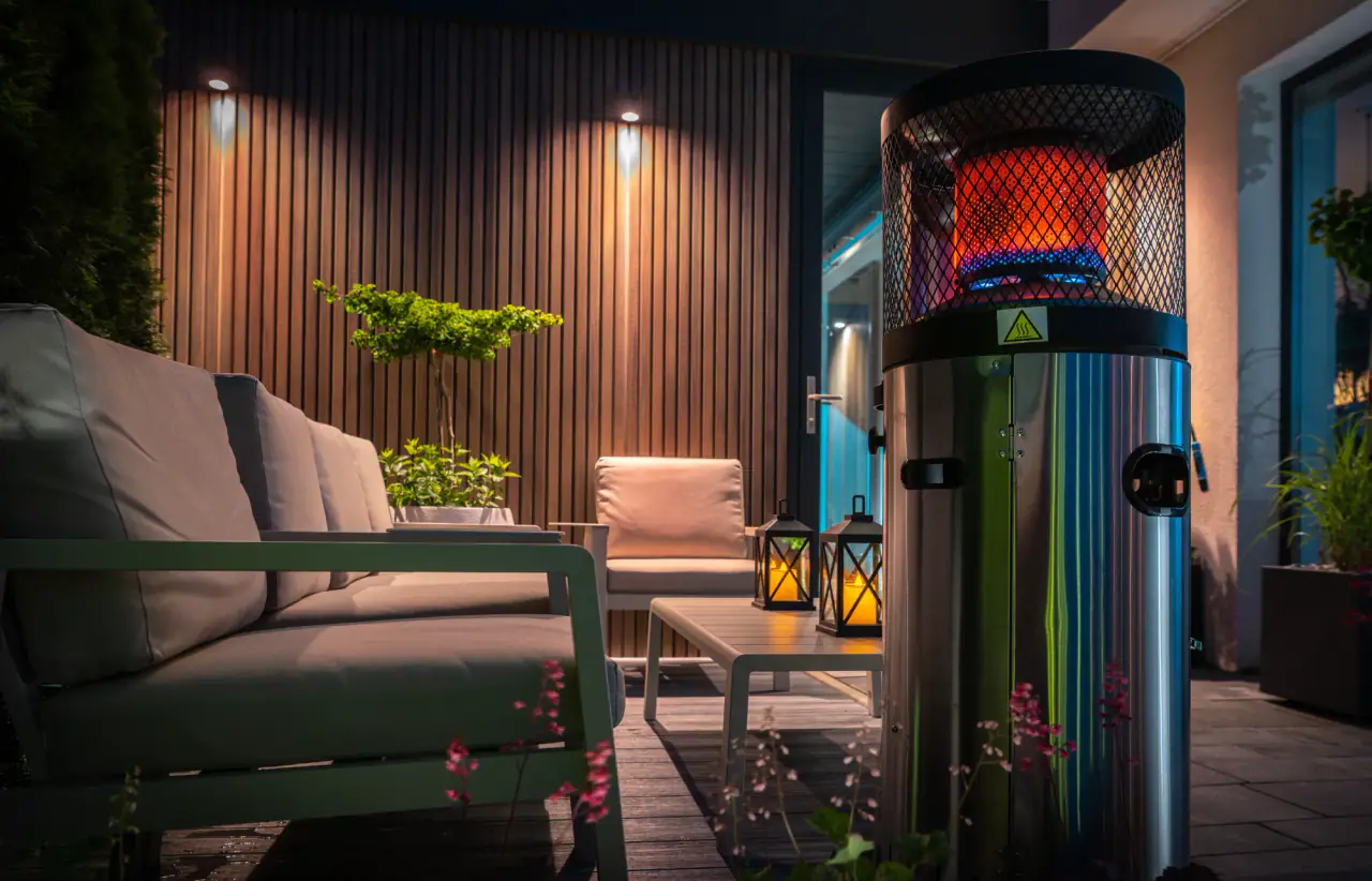 Patio at night lit by warm wall lights and lanterns