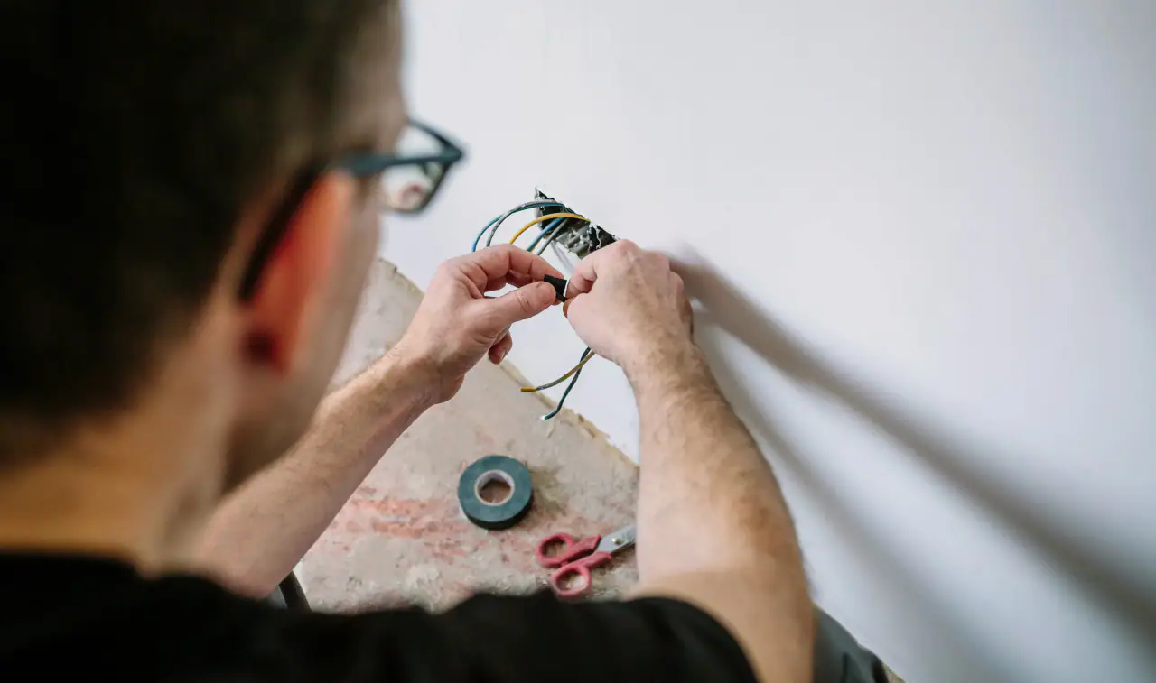 Electrician repairing the wires behind a wall outlet
