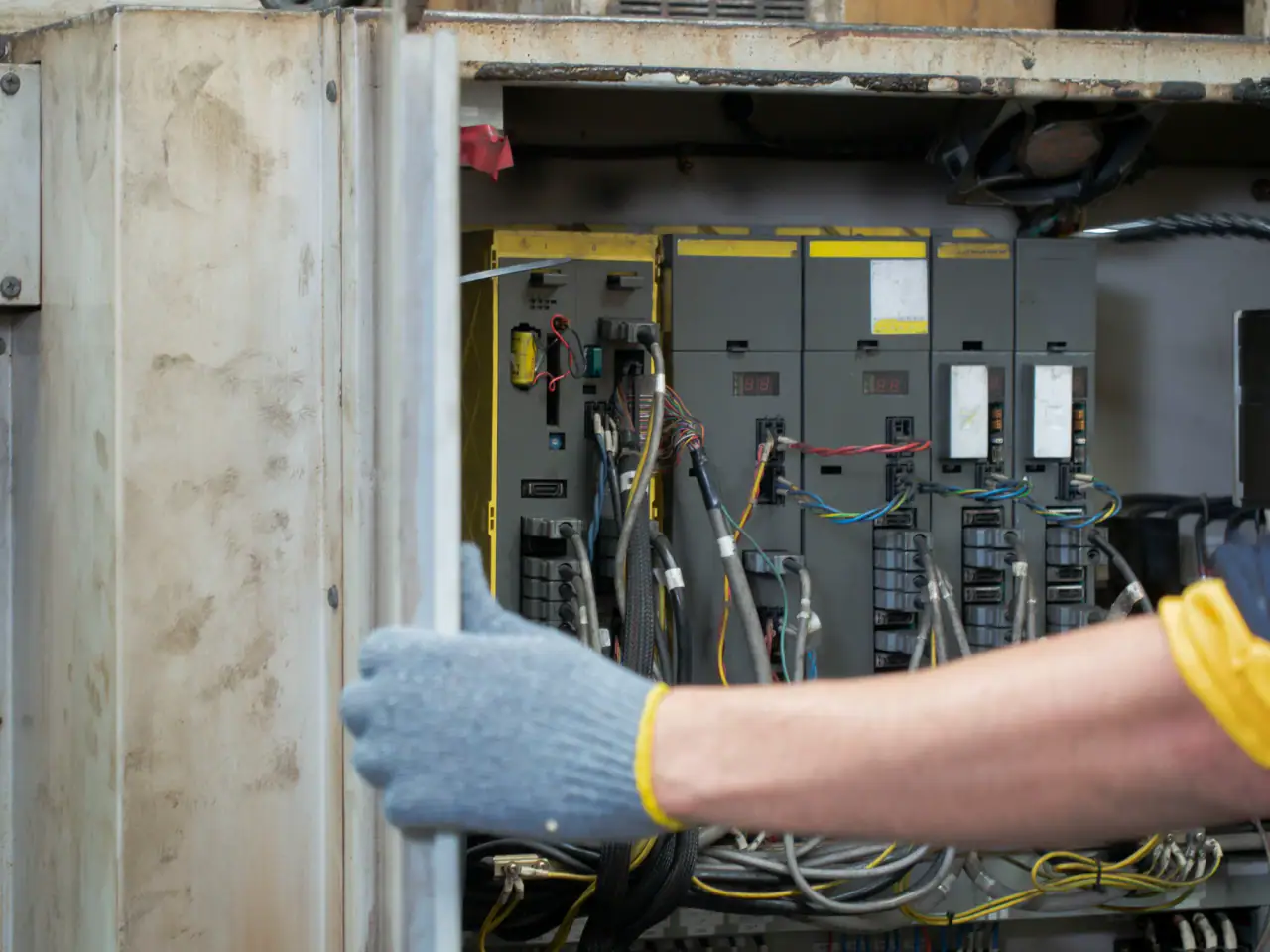 Electrician in work gloves opening an old electrical panel